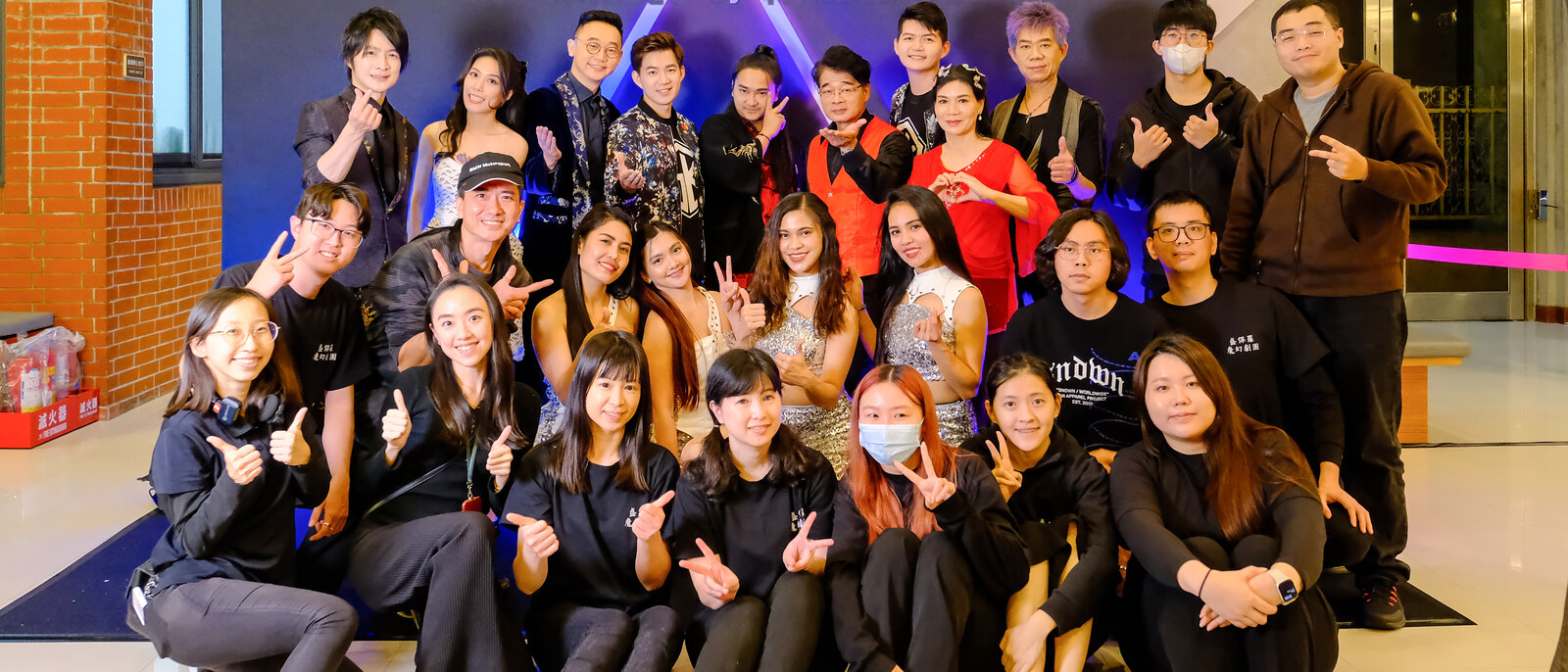 《全明星魔術秀》演出後,穿演出服的魔術師與穿黑衣的幕後工作人員在劇團主視覺背板前全體合影