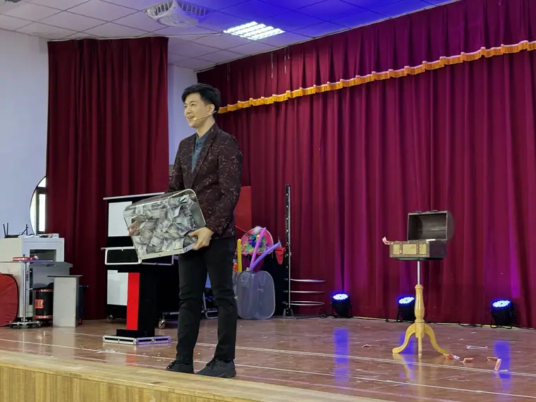 花蓮藝文列車《魔幻兄弟》 演出劇照:男魔術師酒紅亮片西裝側身抱道具箱