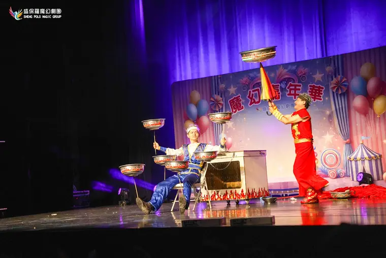 桃園市政府文化局演藝廳《魔幻嘉年華》 演出劇照:轉碟特技段全景:紅、藍傳統戲服演員一坐一站同時轉碟