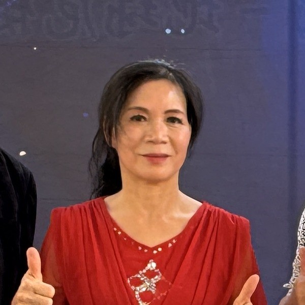 盛保羅魔幻劇團副團長黃桂香,在豐村國小兒童節活動演出後於背板前比讚留影