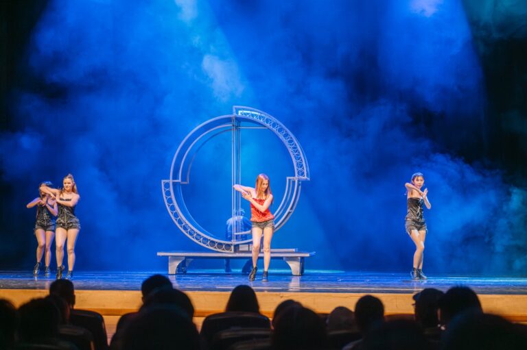 《全明星魔術秀》新竹市文化局演藝廳，舞者在藍光煙霧中的大圓環道具前起舞，前景是觀眾席剪影