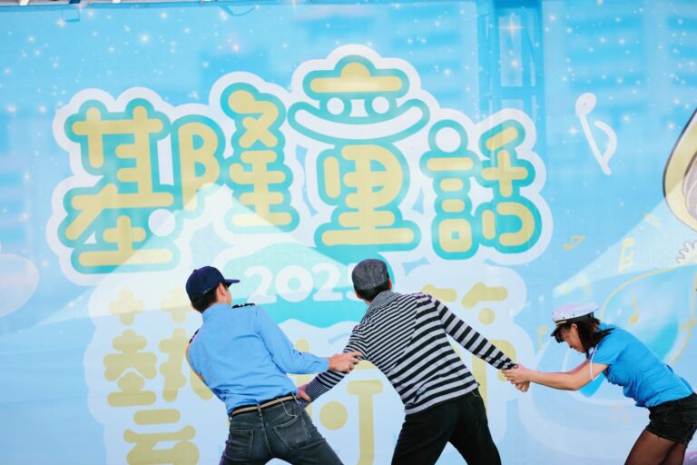 《怪盜神偷》基隆童話藝術節戶外舞台，兩位警探拉住穿條紋衫的神偷，背板寫著「基隆童話藝術節」