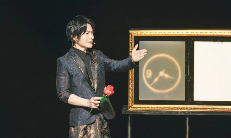《全明星魔術秀》臺北表演藝術中心球劇場,穿織花西裝的魔術師手持紅玫瑰,站在金框道具旁