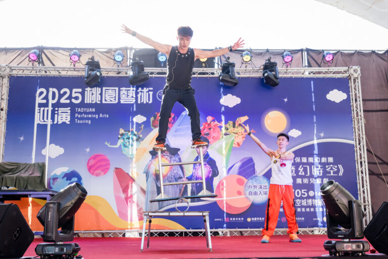 《魔幻時空》大園航空城戶外舞台,特技演員踩在疊高的椅子上張開雙臂