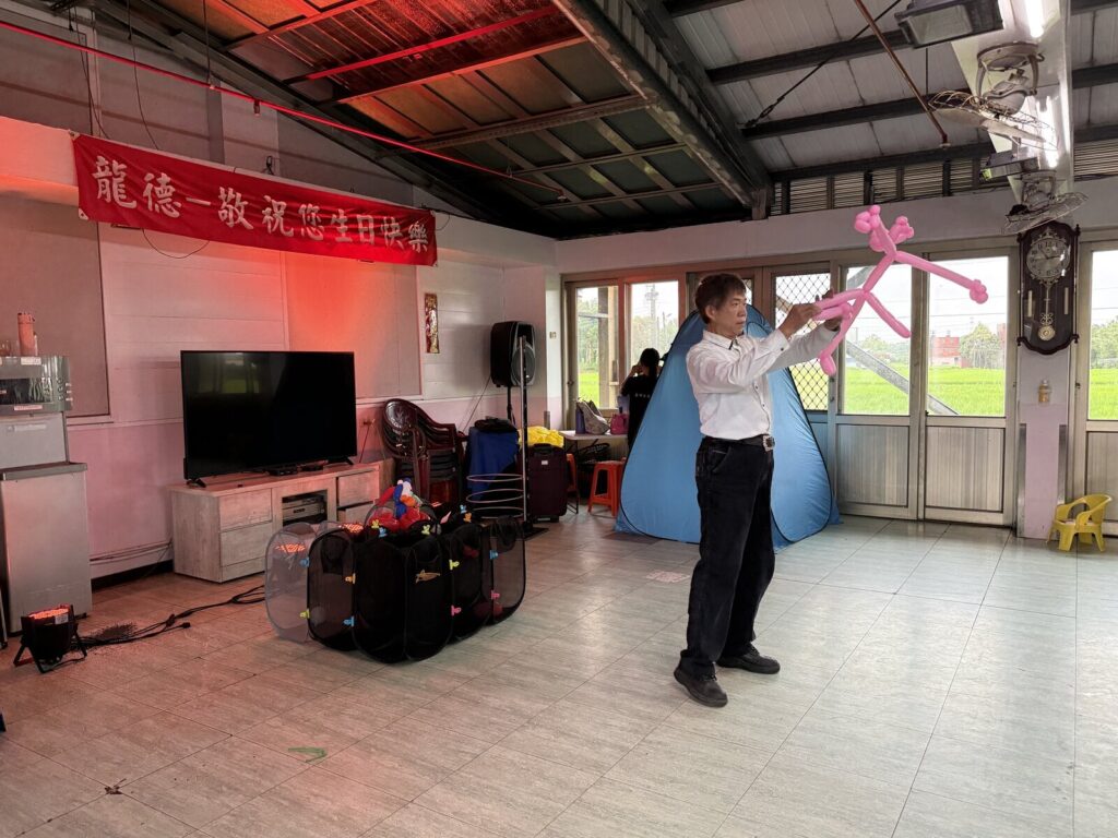 2025 桃園長照機構巡演《魔法時光》，魔術師在新屋龍德老人長照中心活動室舉起氣球造型