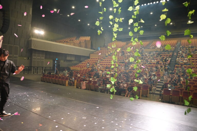 桃園展演中心展演廳《魔法師的考驗-地球危機!》終場灑花,從舞台看向觀眾席,花瓣與綠色葉片從上方落下