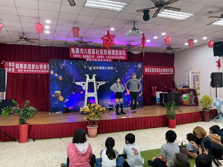 《怪盜神偷》桃園八德瑞祥市民活動中心,舞台掛著社區紅布條,台下孩子坐在草皮上
