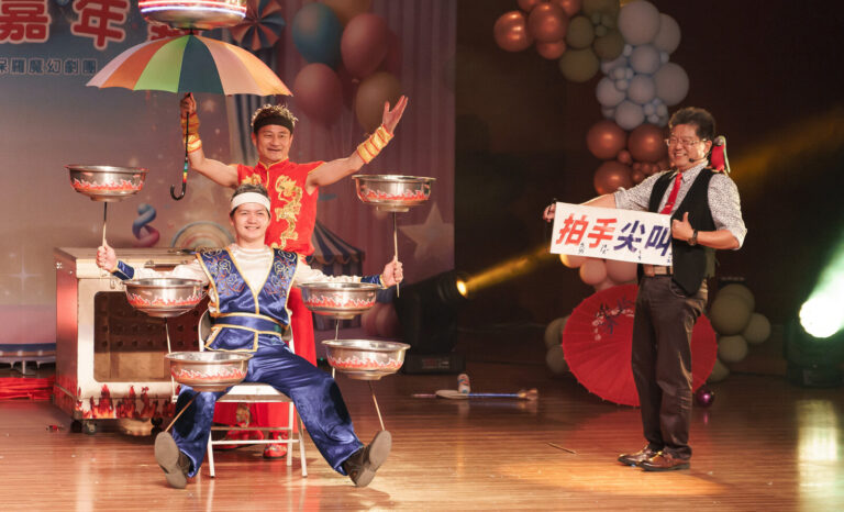 《魔幻嘉年華》臺南新化演藝廳,特技演員撐傘轉盤,旁邊喬克叔叔舉牌