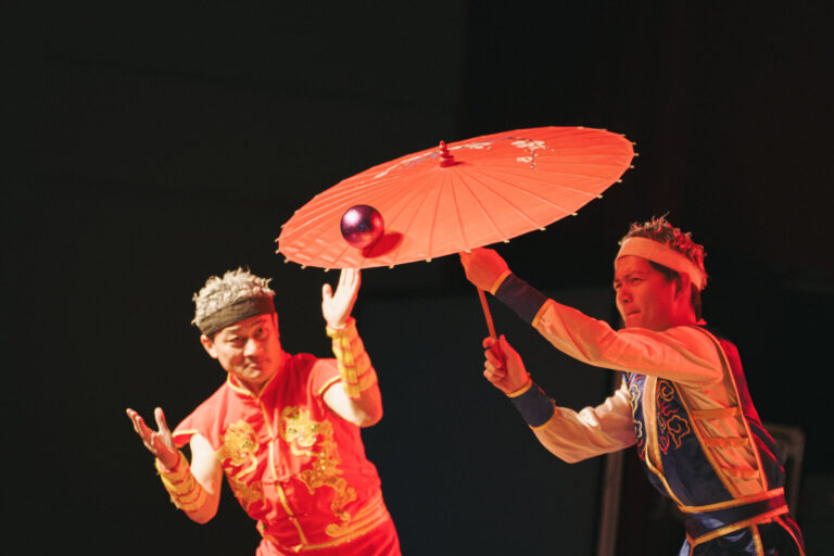 《魔幻嘉年華》臺南新化演藝廳晚場,兩位特技演員以紅傘轉球