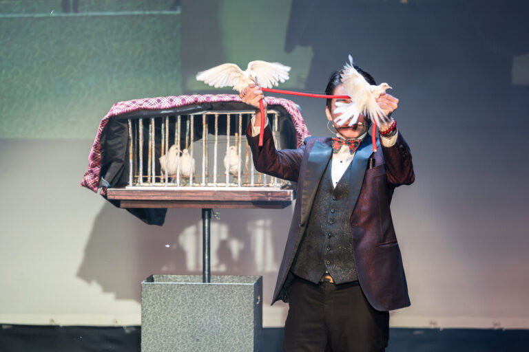 《魔法之夜》桃園市政府文化局演藝廳,魔術師幾米在鴿籠前一拉,兩隻白鴿從紅繩上飛起