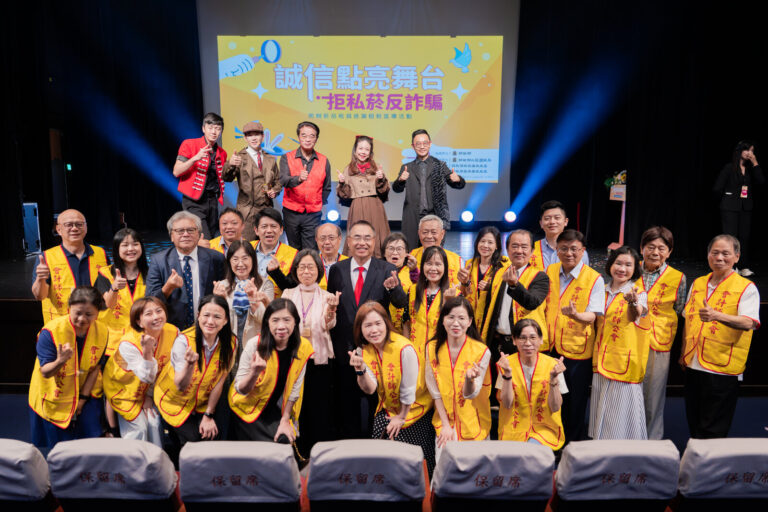 北區國稅局宣導活動演出後,穿黃背心的團體觀眾與演出人員在舞台主視覺前大合照