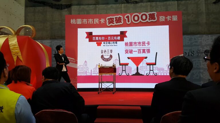 桃園市民卡破百萬記者會,魔術師在魔術桌旁表演,投影「桃園市市民卡 突破一百萬張」