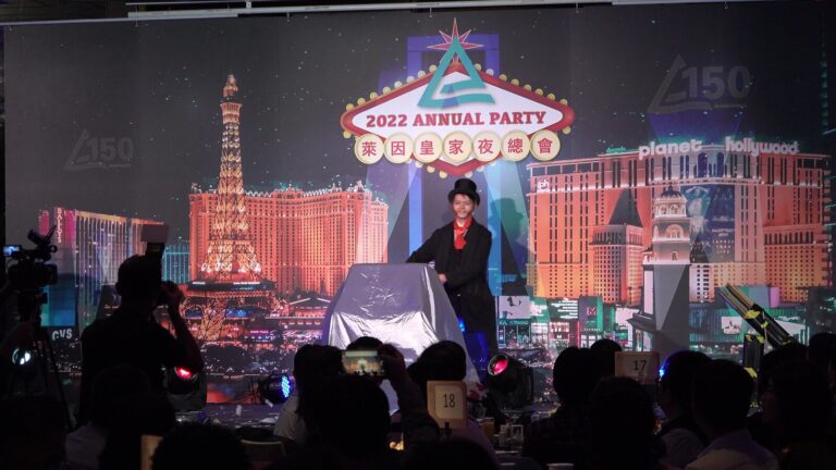 德商 TÜV 2022 年終晚會,魔術師在「2022 ANNUAL PARTY」拉斯維加斯背板前開場,前景是圓桌賓客