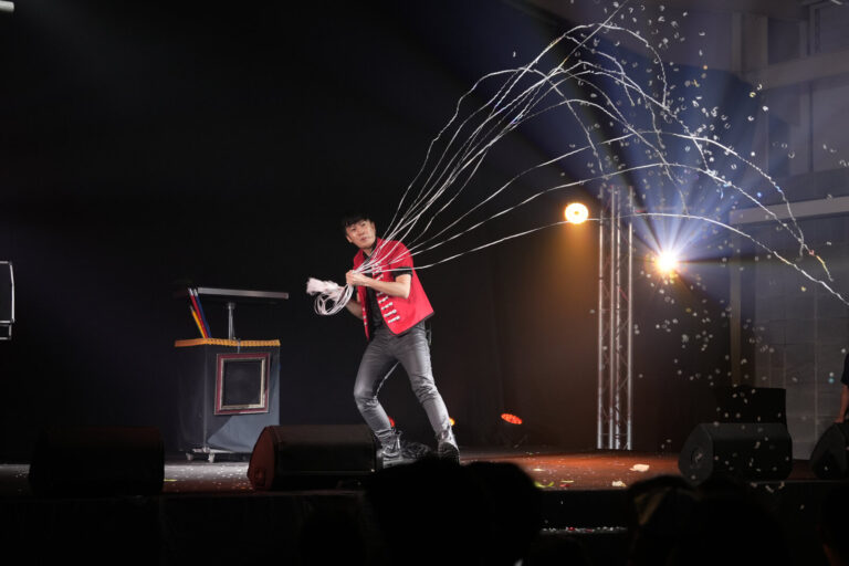 2026 盛保羅魔幻藝術節,紅背心魔術師在中原文創園區室內黑盒舞台甩出彩色紙帶