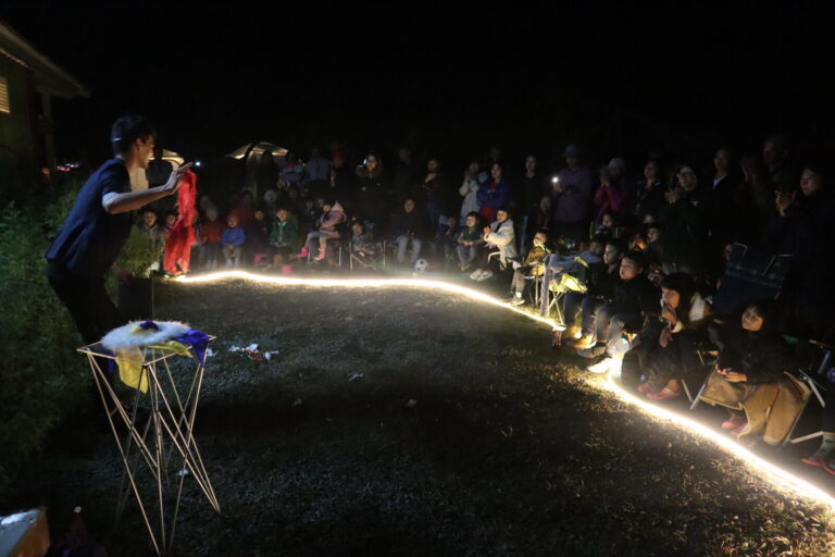 雲起露營區夜間魔術秀，魔術師在燈圈旁表演