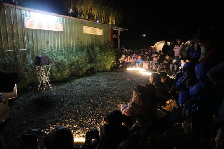 新竹雲起露營區夜間魔術秀，燈帶圍出的表演區外坐滿露營觀眾