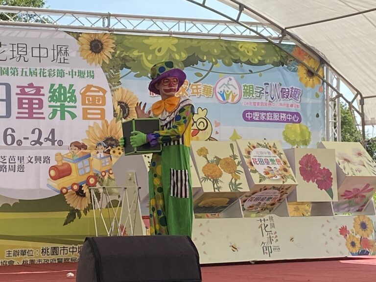 小丑在桃園花彩節中壢場「花田童樂會」背板前表演