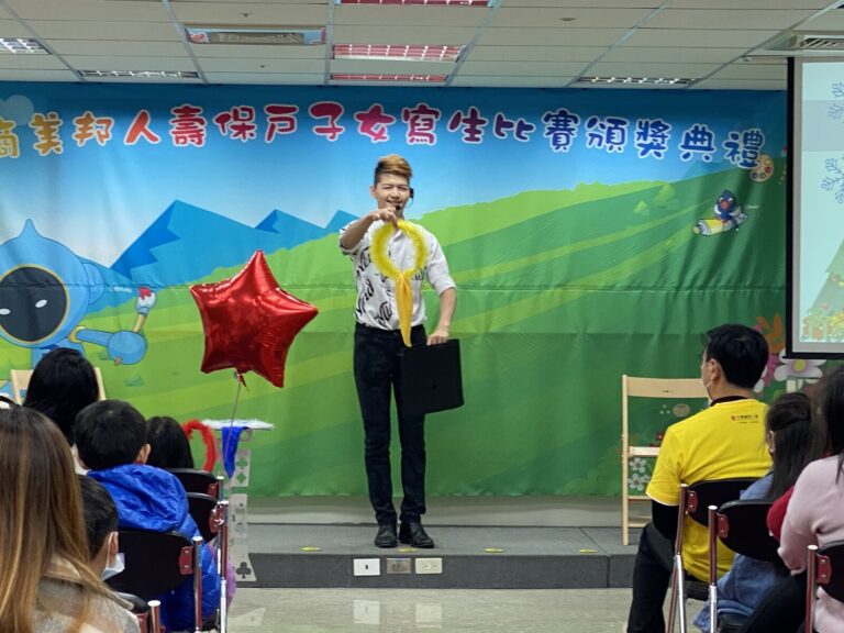 魔術師在三商美邦人壽保戶子女寫生比賽頒獎典禮背板前表演
