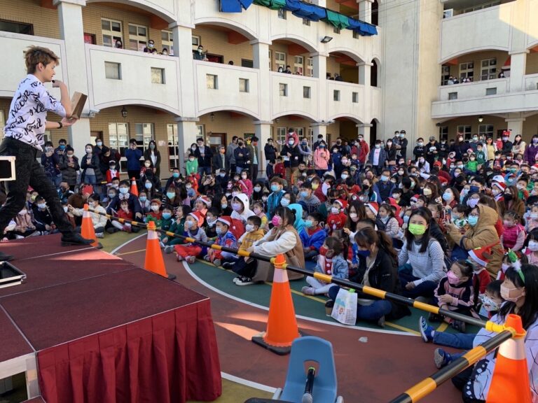 「銀色聖誕之魷魚遊戲派對」魔術秀，魔術師在舞台邊，學校操場坐滿親子