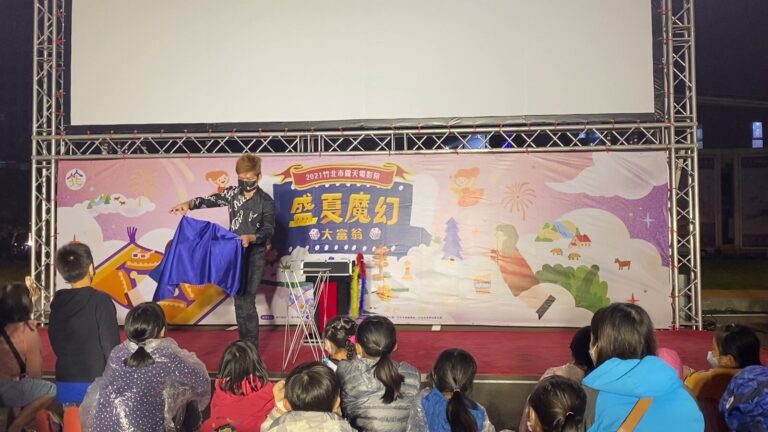 竹北市露天電影院魔術秀,魔術師在「盛夏魔幻大富翁」背板前