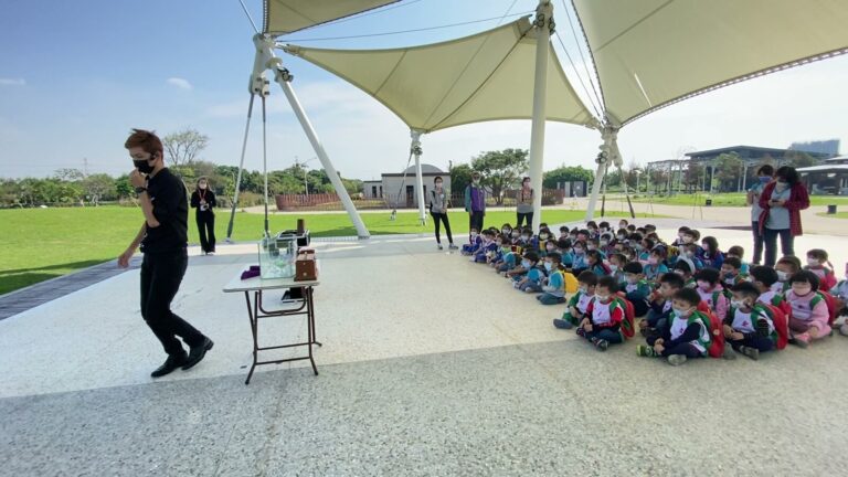 桃園新屋環境教育園區遮陽棚下，魔術師為幼兒園團體表演