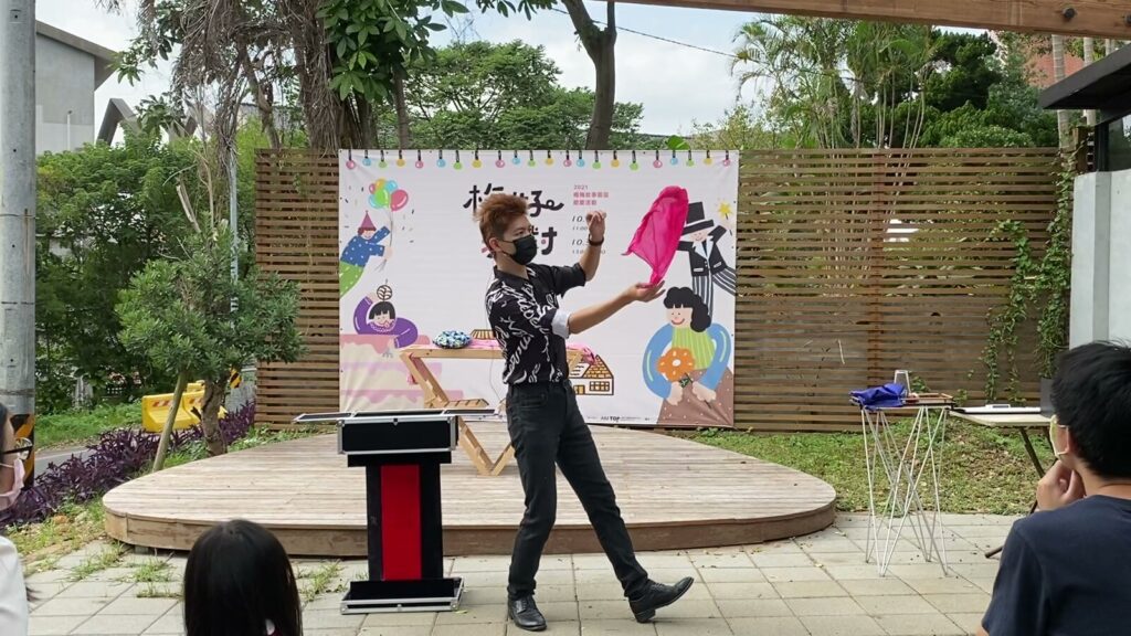 楊梅故事園區「梅好派對」魔術表演，魔術師在背板前表演彩色絲巾