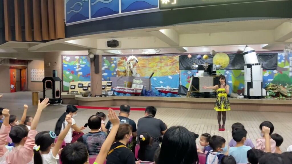 南湖國小《CP魔術秀》，從觀眾後方看向集會場舞台，學生與家長坐在地板上