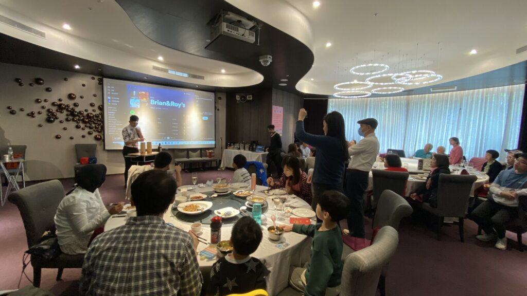 岡原公司尾牙午宴宴會廳全景,魔術師在投影幕前表演