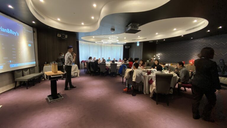岡原公司尾牙午宴,魔術師在宴會廳前方表演,賓客圍桌觀看