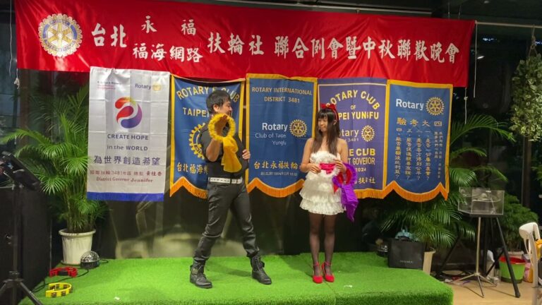 扶輪社聯合例會暨中秋聯歡晚會，兩位表演者在社旗前演出