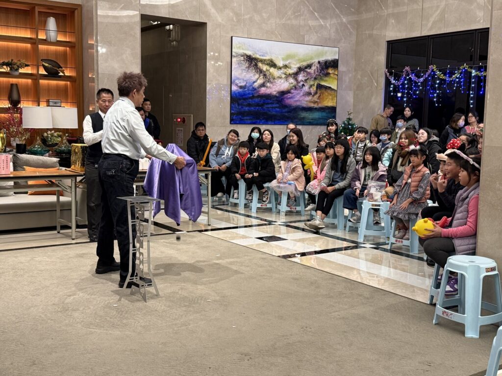 鉅慶銘鑄社區大廳的聖誕聯歡活動魔術表演,住戶坐在兩側觀看