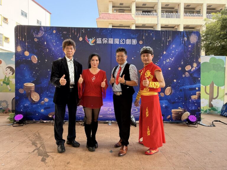 盛保羅魔幻劇團四位演出人員在豐村國小兒童節演出後，於劇團背板前合影