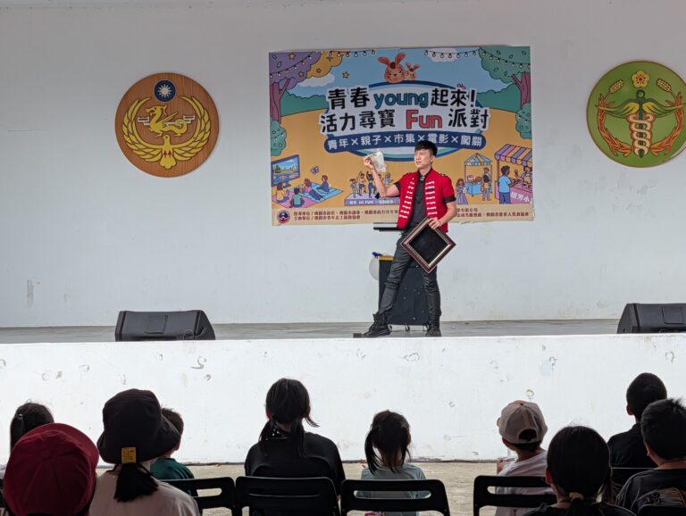 魔術師在虎頭山創新園區「青春 young 起來」背板前表演，前排觀眾背影